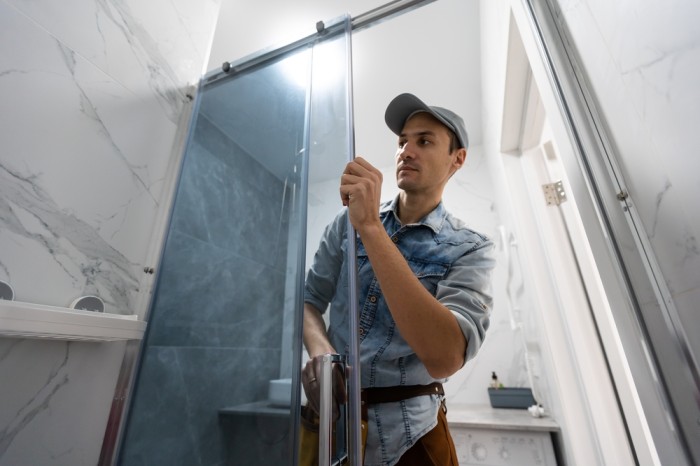 Technician performing shower door adjustment in a Grand Junction bathroom