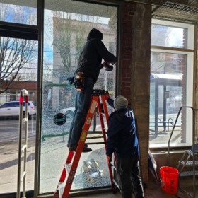 Technician performing commercial window repair on a storefront in Glenwood Springs