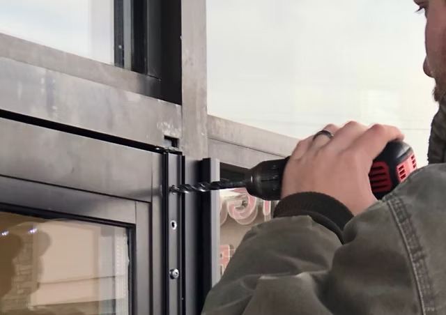 Technician repairing hinge on a commercial door in Grand Junction